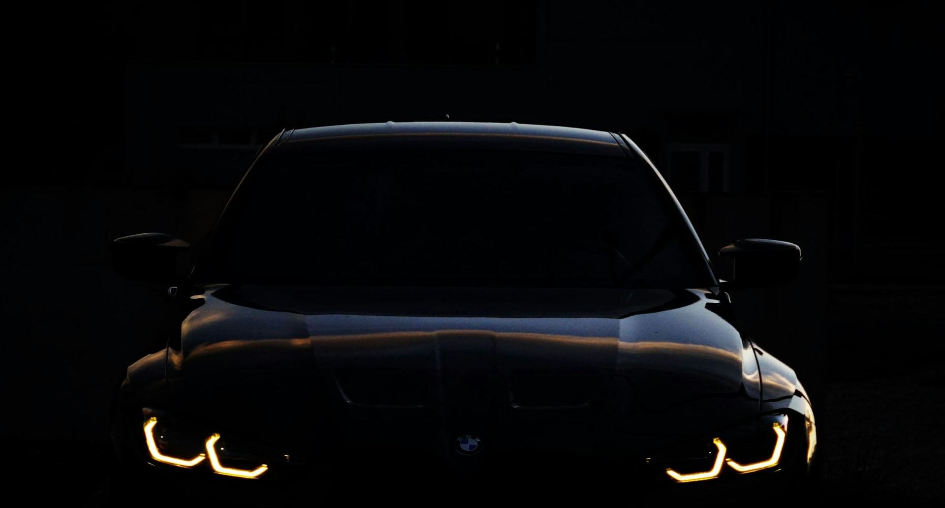 A new car waiting at night with its running lights on